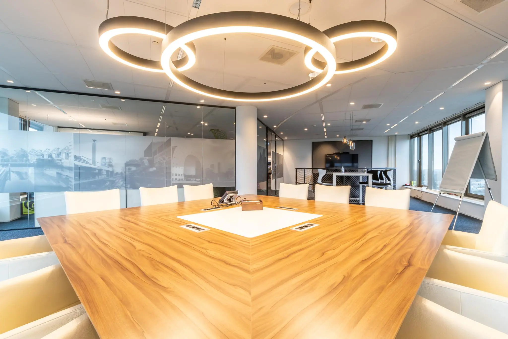 Vergaderruimte aan de Fascinatio Boulevard met modern houten vergadertafel, designverlichting en uitzicht op glazen kantoorwanden.